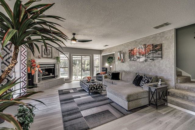 living room featuring wood-type flooring, a textured ceiling, and ceiling fan