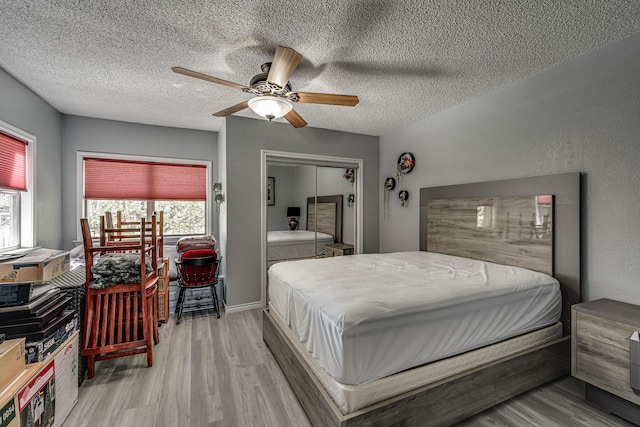 bedroom with a closet, ceiling fan, light wood-style floors, and a textured ceiling