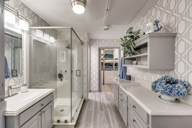 bathroom featuring hardwood / wood-style flooring, walk in shower, vanity, and a textured ceiling