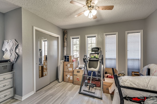 bedroom with a textured ceiling, ceiling fan, and light hardwood / wood-style flooring