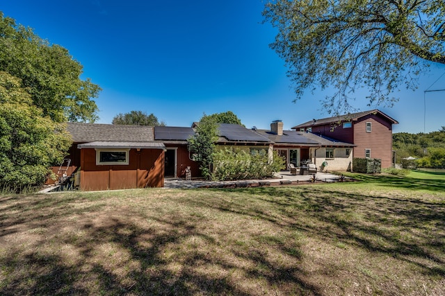 back of property featuring a lawn, solar panels, and a patio area