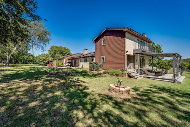 back of property with a balcony, a wooden deck, and a lawn