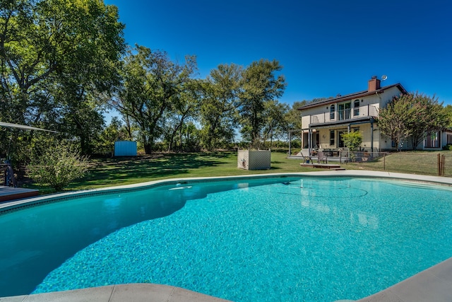 view of swimming pool featuring a storage shed and a yard