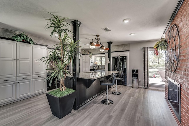 office space featuring visible vents, a sink, light wood-type flooring, heating unit, and a textured ceiling