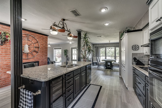 kitchen featuring white cabinets, sink, beverage cooler, a center island with sink, and a textured ceiling