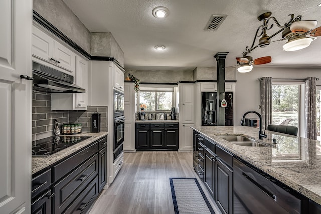 kitchen with a healthy amount of sunlight, black appliances, white cabinetry, and sink