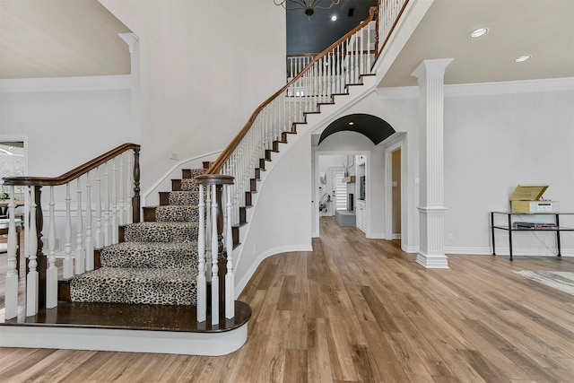 foyer featuring crown molding, hardwood / wood-style flooring, decorative columns, and a towering ceiling