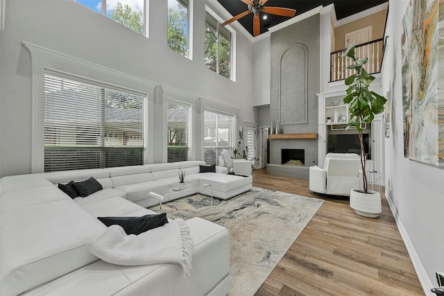 living room with ornamental molding, a brick fireplace, a healthy amount of sunlight, and hardwood / wood-style floors