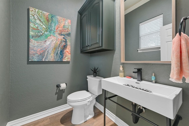 bathroom with hardwood / wood-style floors, toilet, crown molding, and sink