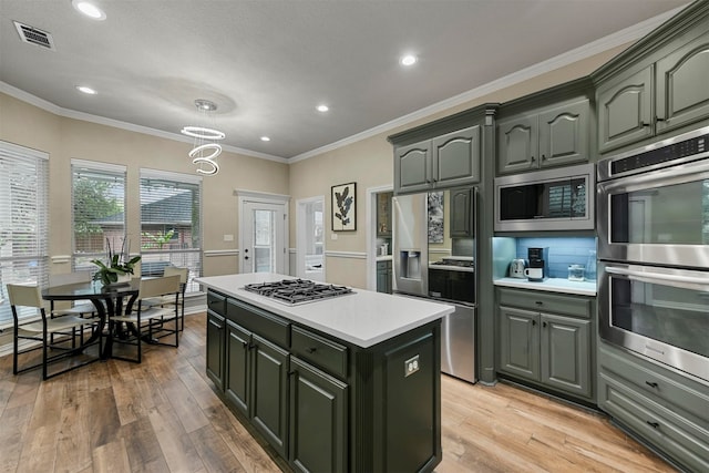 kitchen featuring a notable chandelier, crown molding, light hardwood / wood-style floors, a kitchen island, and appliances with stainless steel finishes