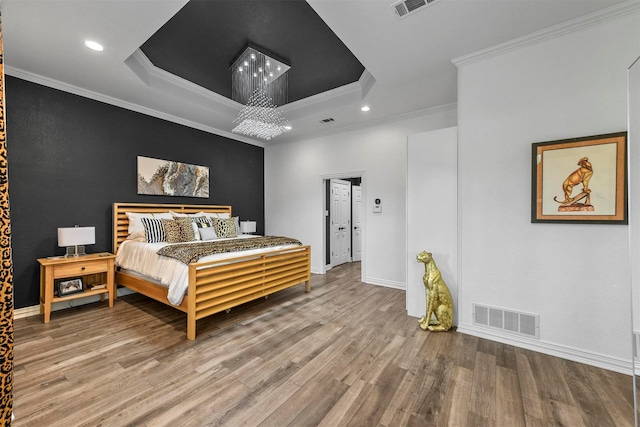 bedroom with a raised ceiling, ornamental molding, and hardwood / wood-style floors