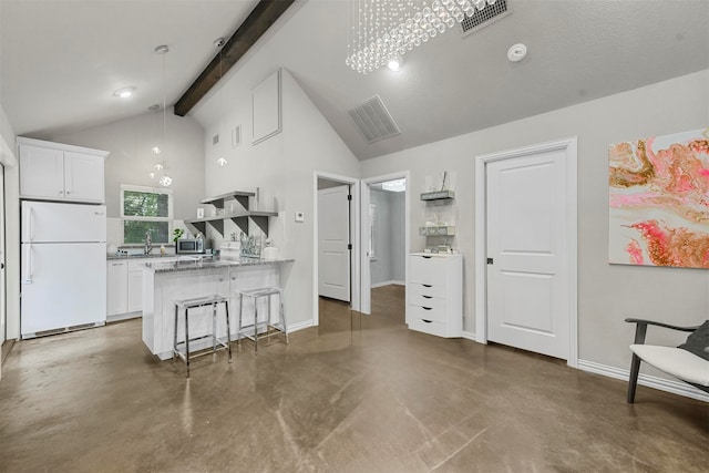 kitchen featuring beamed ceiling, decorative light fixtures, white refrigerator, and white cabinetry