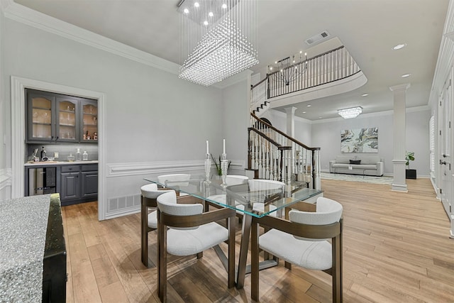 dining space with wine cooler, decorative columns, light hardwood / wood-style flooring, and ornamental molding