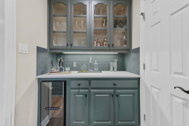 bar with tasteful backsplash, gray cabinets, and beverage cooler