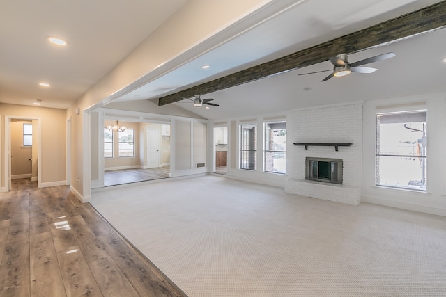 unfurnished living room featuring a brick fireplace, vaulted ceiling with beams, light hardwood / wood-style flooring, and a healthy amount of sunlight