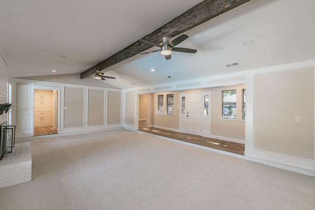 unfurnished living room featuring ceiling fan, vaulted ceiling with beams, a fireplace, and light carpet