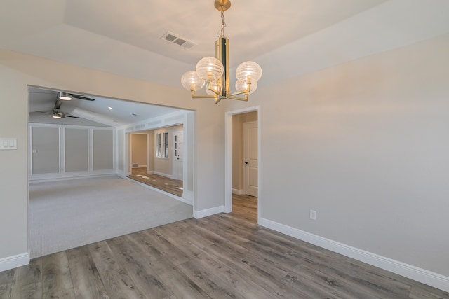 unfurnished room with ceiling fan with notable chandelier, wood-type flooring, and lofted ceiling