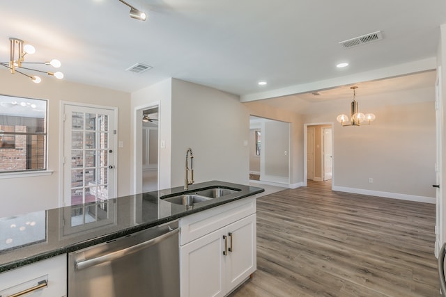 kitchen featuring dark stone countertops, white cabinets, hardwood / wood-style flooring, stainless steel dishwasher, and sink