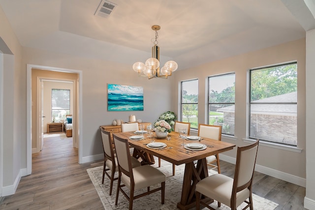 dining room featuring light hardwood / wood-style flooring, a chandelier, and a tray ceiling