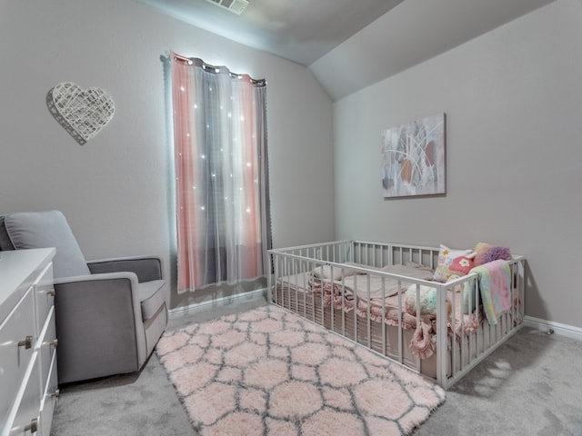 carpeted bedroom featuring a nursery area and lofted ceiling