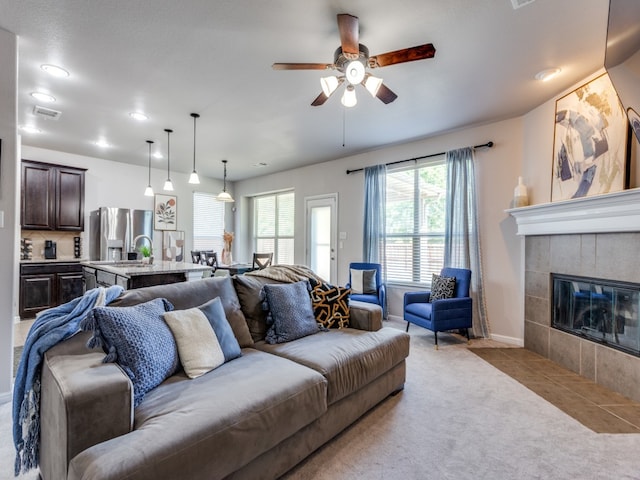 living room with a fireplace, light carpet, and ceiling fan