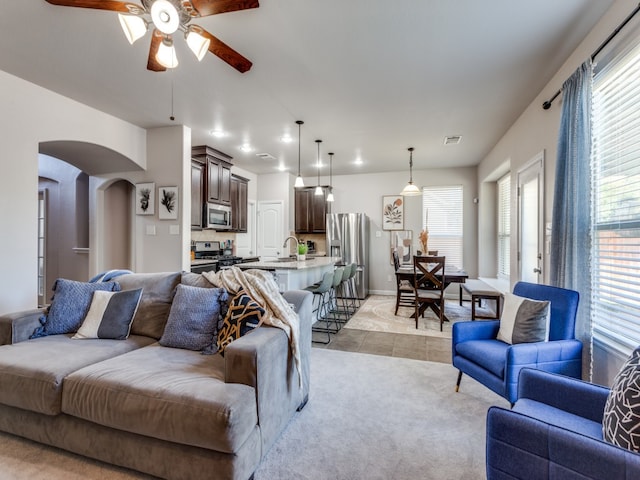 living room with ceiling fan, sink, and light tile patterned floors