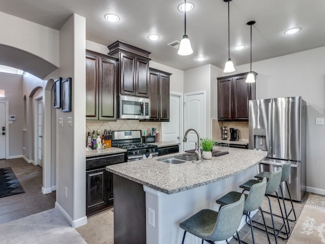 kitchen featuring a center island with sink, sink, stainless steel appliances, and tasteful backsplash