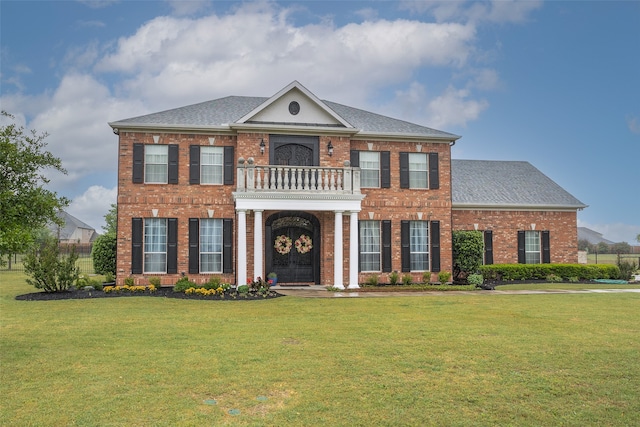 colonial-style house featuring a front yard and a balcony