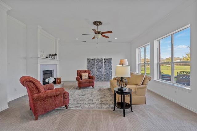 living room with a fireplace, ceiling fan, crown molding, and light carpet