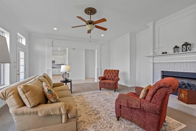 carpeted living room featuring a fireplace, ceiling fan, and crown molding