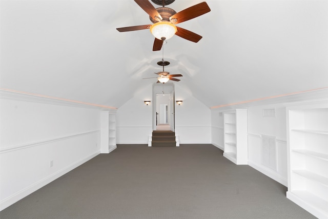 additional living space with dark colored carpet, ceiling fan, built in features, and vaulted ceiling