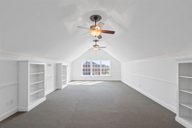 bonus room with ceiling fan, dark carpet, vaulted ceiling, and built in shelves