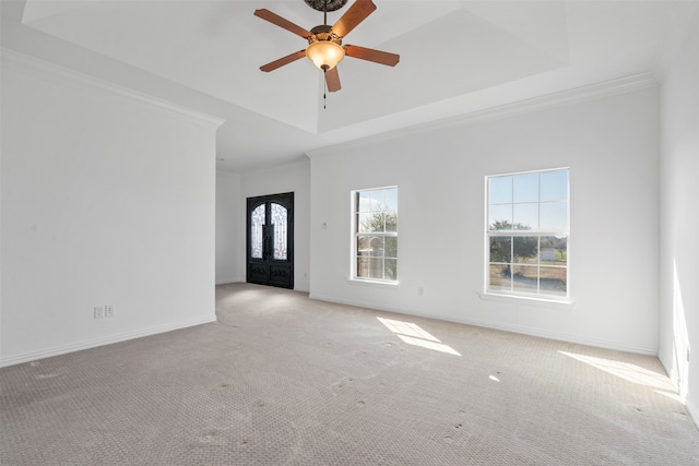 carpeted spare room with a tray ceiling, ceiling fan, french doors, and ornamental molding