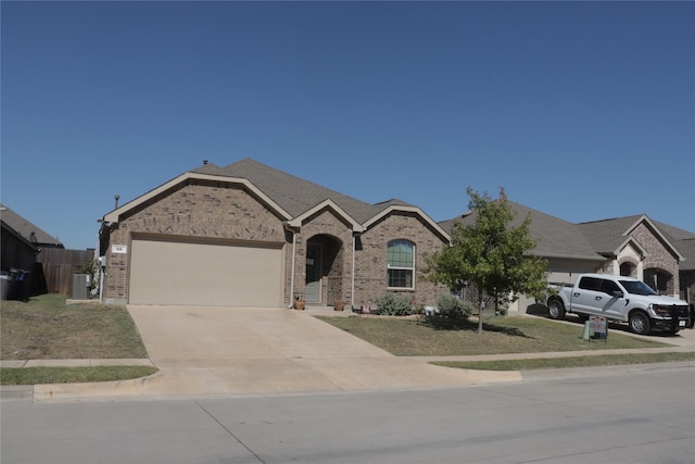 view of front of home featuring a front yard, central AC, and a garage