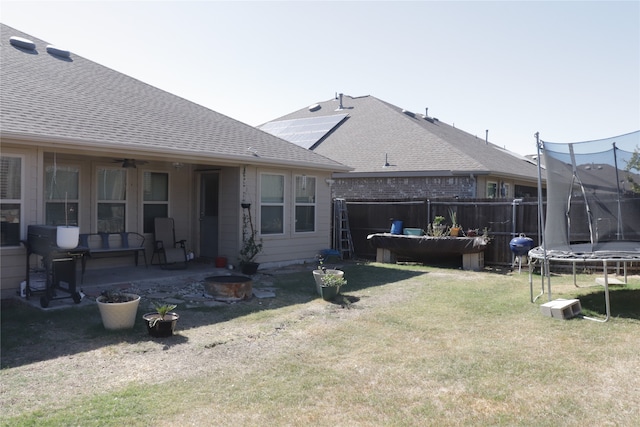 rear view of property with a yard, a trampoline, a patio, and ceiling fan