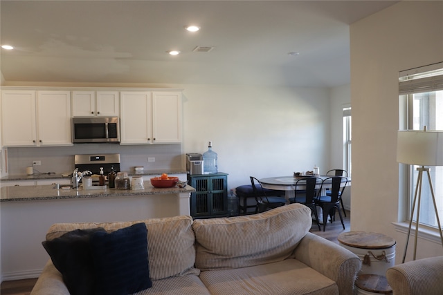 kitchen featuring tasteful backsplash, sink, stainless steel appliances, white cabinets, and light stone counters