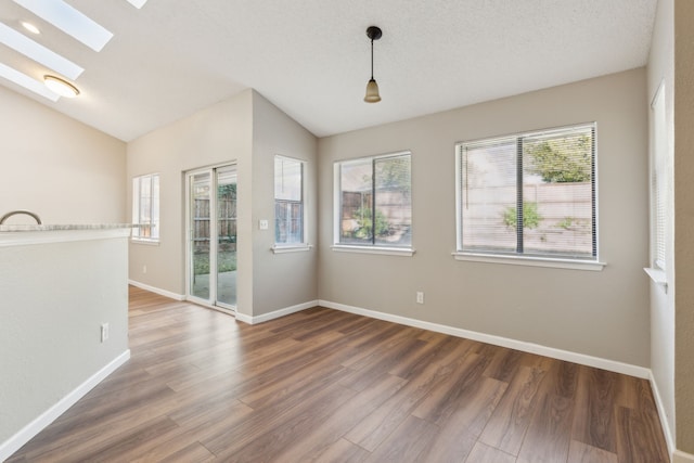 spare room with lofted ceiling with skylight, a textured ceiling, and dark hardwood / wood-style flooring