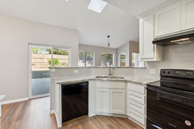 kitchen with vaulted ceiling with skylight, sink, black appliances, and white cabinets