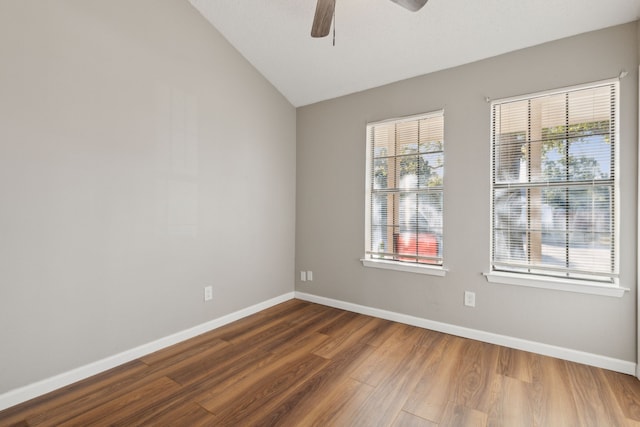 spare room featuring vaulted ceiling, a healthy amount of sunlight, dark hardwood / wood-style flooring, and ceiling fan