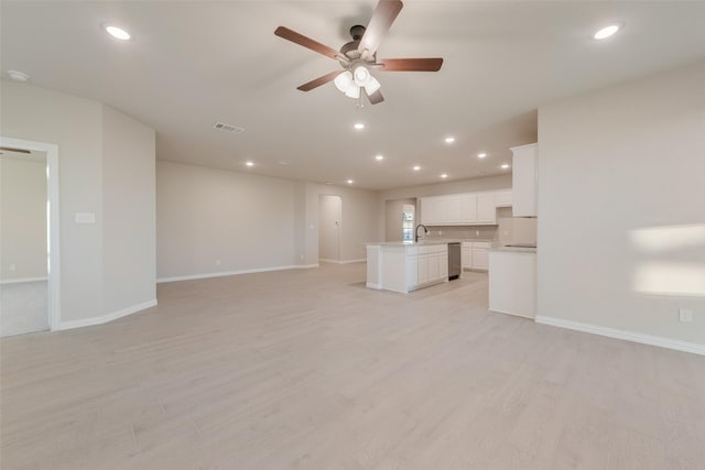 unfurnished living room featuring light hardwood / wood-style flooring, ceiling fan, and sink