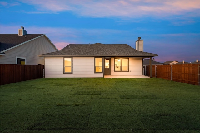 back house at dusk with a yard and a patio area