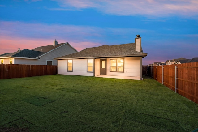 back house at dusk with a lawn