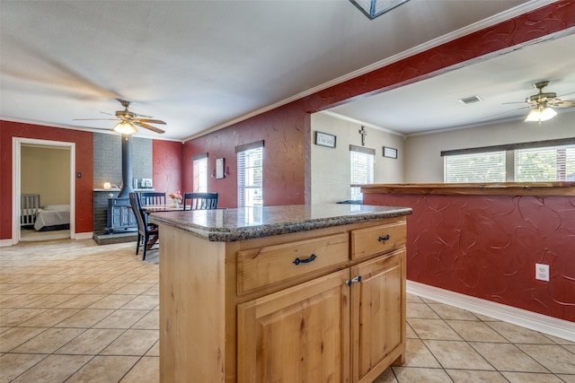 kitchen featuring ceiling fan, a center island, light tile patterned flooring, and crown molding