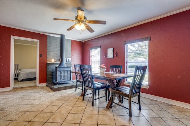 tiled dining space featuring ornamental molding, a wood stove, and ceiling fan