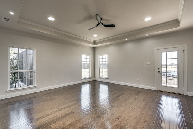 unfurnished room with a raised ceiling, ornamental molding, ceiling fan, and dark wood-type flooring