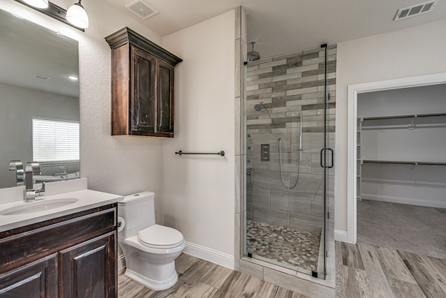 bathroom featuring wood-type flooring, a shower with door, vanity, and toilet