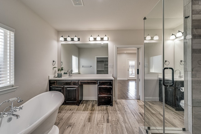 full bathroom with hardwood / wood-style floors, vanity, separate shower and tub, and a wealth of natural light