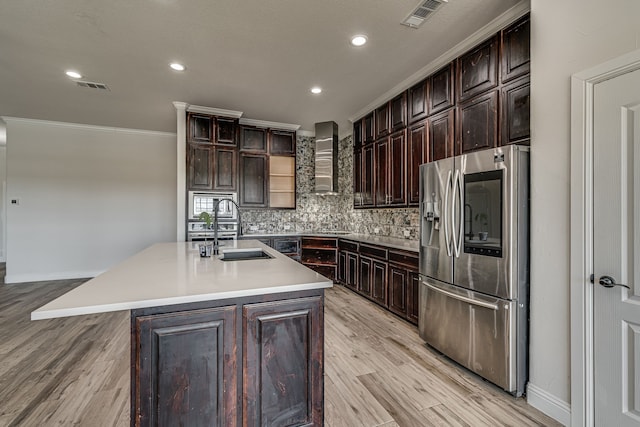 kitchen featuring a kitchen island with sink, wall chimney exhaust hood, light hardwood / wood-style flooring, appliances with stainless steel finishes, and crown molding