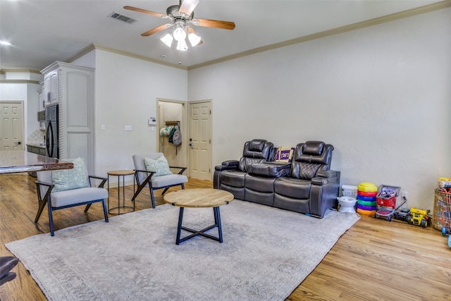 living room with ornamental molding, light wood-type flooring, and ceiling fan