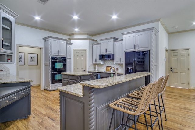 kitchen featuring black appliances, gray cabinets, light wood-type flooring, and a kitchen island